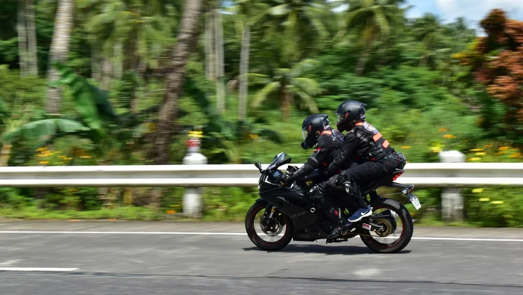 Two motorcycle riders, male and female, speeding on the highway