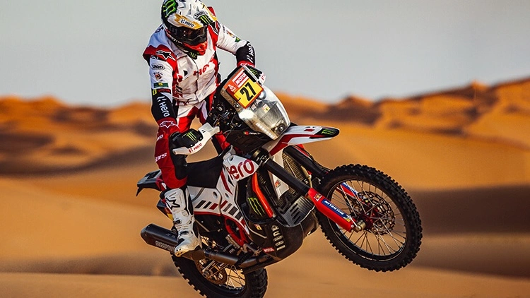 Motorcycle rider, male on full gear, performing tricks on the desert