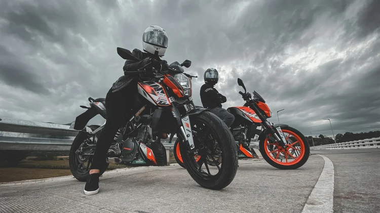 Two motorcycle riders, male and female, parked on the street